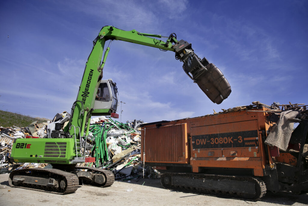 En gripklo lyfter en soffa ur en container.