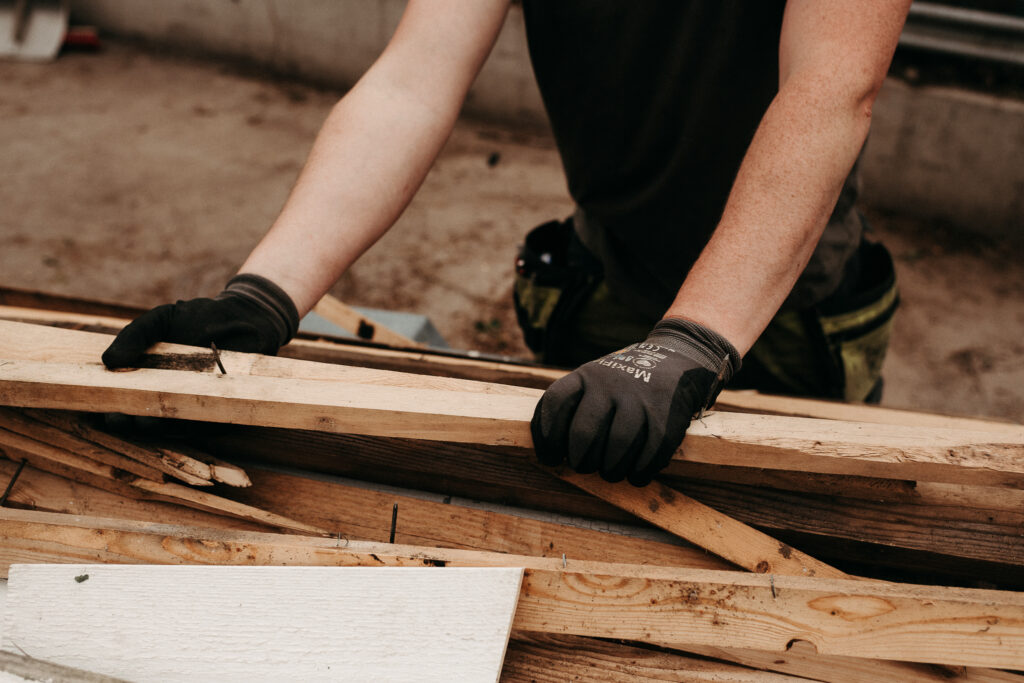 Ett par handskförsedda händer håller i en träplanka